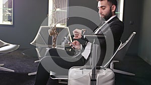 Businessman using mobile phone at the airport in the waiting lounge