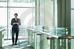 Businessman using mobile phone in corridor at modern office building