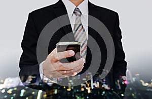 Businessman using mobile phone with defocus cityscape at night with Bokeh background