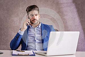 Businessman using mobile phone and laptop while working at the office