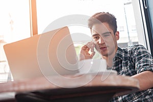 Businessman using mobile phone while lookingat laptop on wooden photo