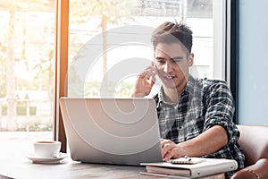 Businessman using mobile phone while lookingat laptop on wooden photo