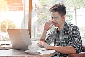 Businessman using mobile phone while lookingat laptop on wooden photo