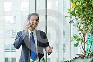 Businessman using mobile phone near office window at receptions