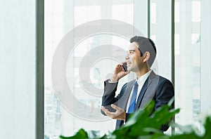 Businessman using mobile phone near office window at receptions