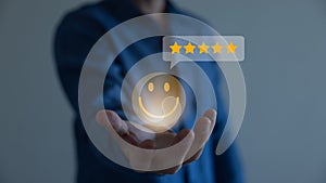 Businessman using a mobile phone to point to a smile face and five stars icon, representing positive reviews