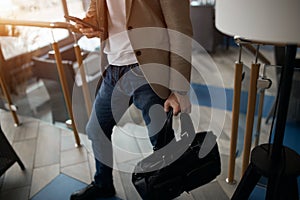 Businessman using mobile phone while walking in the office