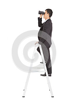 Businessman using a pair of binoculars standing on stair