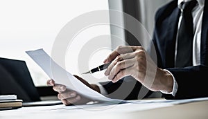 A businessman using a pen to point a pie chart on a document, he is reviewing financial documents from the finance department.