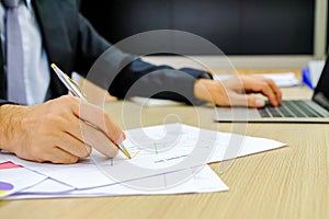 Businessman using red pen writing in notepad on office