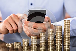 Businessman Using Smart Phone For Calculating Coins