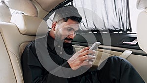 Businessman using smart phone checking social media in luxury car interior