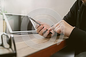 businessman using smart phone for mobile payments online shopping and digital tablet docking keyboard computer on wooden desk in