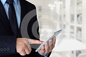 Businessman using smart phone over blur office background with c