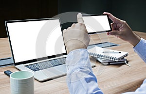 Businessman using smart phone to take picture of laptop screen and white screen background mock up on display laptop and smart