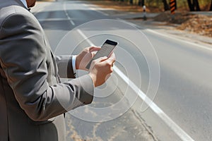 businessman using smartphone app to book a ride, standing by the road