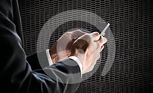 Businessman using smartphone, on blurred defocus black metal net background