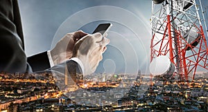 Businessman using smartphone with double exposure cityscape in sunset, and telecommunication towers