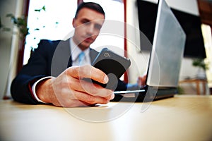 Businessman using smartphone. Focus on smartphone.