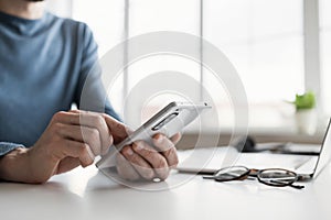 Businessman using smartphone in office. Young man using laptop computer and phone at home.