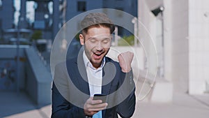 Businessman Using Smartphone and Reacting to Success. Handsome professional successful business man reaching personal