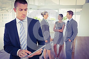 Businessman using tablet with colleagues behind him