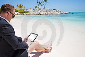 Businessman using tablet computer on the beach