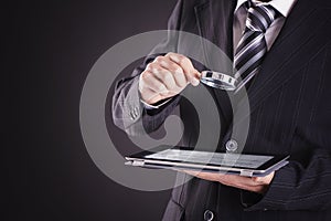 Businessman using tablet computer with magnifying glass