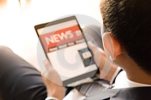 Businessman using tablet computer, reading news