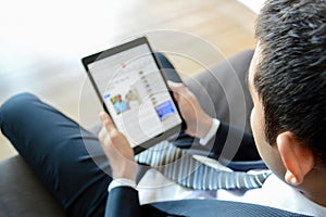 Businessman using tablet computer while sitting on the couch