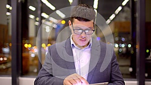 Businessman using tablet computer touchscreen in the night office.