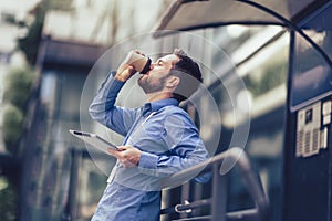Businessman using tablet and drinking coffee outside of his job