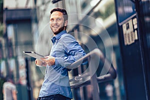 Businessman using tablet and drinking coffee outside of his job