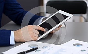 Businessman using tablet at meeting, closeup of hands. Business operations concept