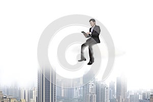 Businessman using tablet and sitting on cloud