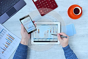 Businessman using tablet and smartphone and checking stock market data