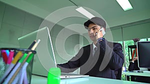 Businessman is using telephone and listening to the conversation while working on computer in the office.
