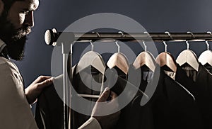 Businessman in vest, row of suits in shop. It is in the showroom, trying on clothes, posing. Stylish man in a cloth