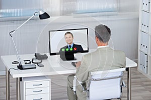 Businessman Videoconferencing With Partner On Computer At Desk