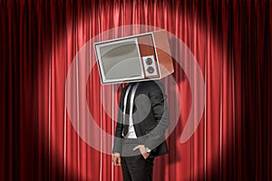 Businessman with vintage tv set instead of head on red stage curtains background