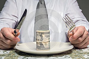 Businessman with wad of dollars served on plate