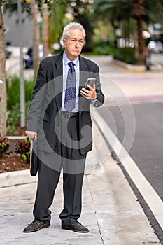 Businessman waiting for his uber lyft ride and tracking arrival on the phone app