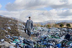 Businessman walking across on landfill, large pile of waste. Consumerism versus pollution concept. Corporate social