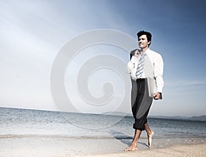 Businessman walking along a beach with laptop