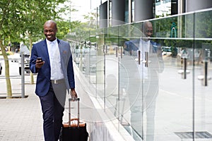 Businessman walking with bag and looking at mobile phone