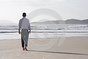 Businessman walking barefoot on a beach