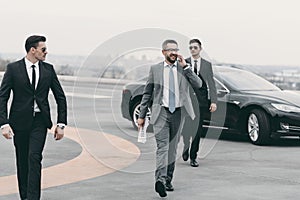 businessman walking with bodyguards on helipad and talking