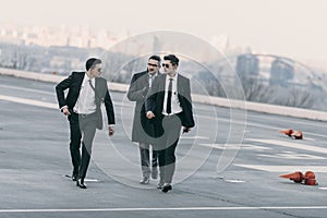 businessman walking with bodyguards in sunglasses and suits