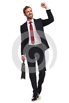 Businessman walking and celebrating while looking up to side