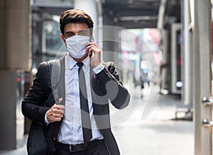 Businessman walking in city with very small amount of people during covid-19 outbreak make phone call and wearing mask